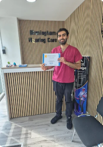 A Male Nurse who have received professional training in removing earwax showcasing his certification.