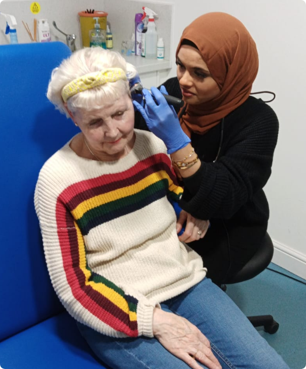 Audiologist performing ear examination on patient in clinic setting
